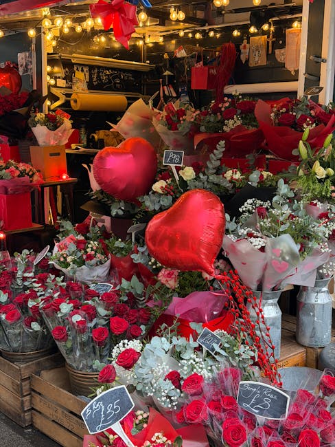 A vibrant floral display at Honoroak Florist showing an assortment of fresh red roses, white baby's breath, and greenery arranged in baskets and bouquets. Prominent among the arrangements are heart-sh