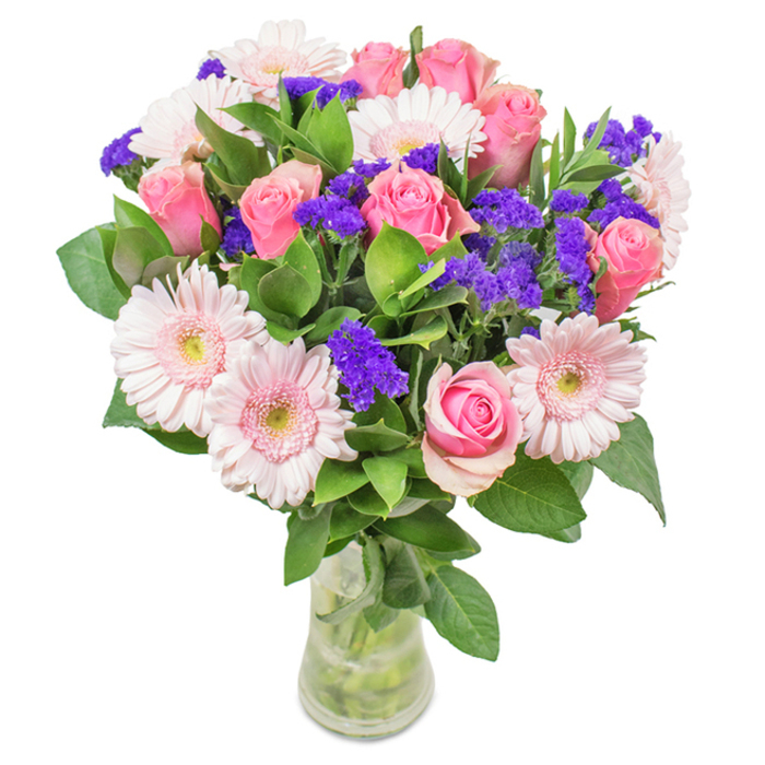 On a seamless white surface, this striking bouquet arranged by Honor Oak Florist features a harmonious, romantic blend of flowers designed to convey joy and affection. Approximately seven to nine pink roses-many in bud or just beginning to bloom-share their classical spirals and sumptuous textures, while five to seven pale pink gerbera daisies fan out their broad, delicately layered petals, the nearly white centers glowing softly in natural light. Clusters of vibrant purple statice or limonium weave through the arrangement, injecting lively texture and providing a vivid counterpoint that evokes the colorful stalls of Honor Oak Market. Rich green foliage offers a base of vitality, enhancing the visual richness and hinting at the natural freshness found along the leafy streets near Peckham Rye Park. The bouquet rests in a clear glass vase, with stems arranged tidily in crisp water to evoke freshness as though just delivered. Suitable for occasions from heartfelt birthdays to tender anniversaries, or as an elegant accent in a sunlit Honor Oak home, this bouquet combines visual beauty, expert craftsmanship, and the warmth of a local florist's touch.